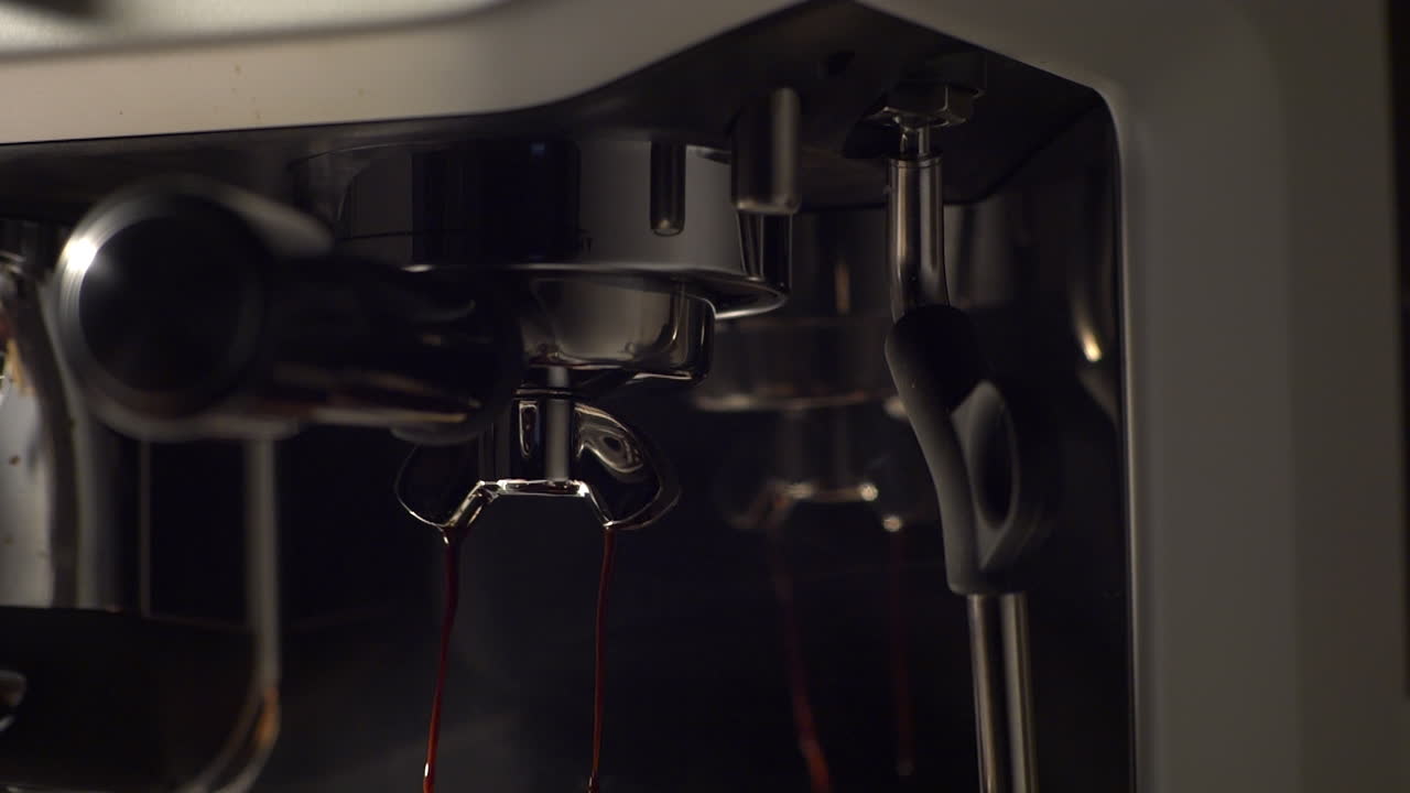 Close-up em câmera lenta de expresso encorpado fluindo de um portafiltro durante a extração em uma máquina de expresso premium. Tons escuros, superfícies de metal brilhante e a textura da crema enfatizam o luxo e o café de alta qualidade.