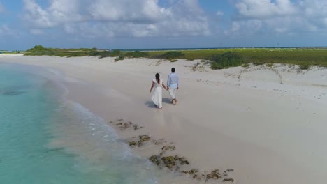 couple walking on sand beach hands to hands