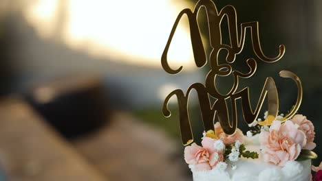 shot of a beautifully decorated floral wedding cake sitting on a pedestal right next to a pool during a summer wedding reception