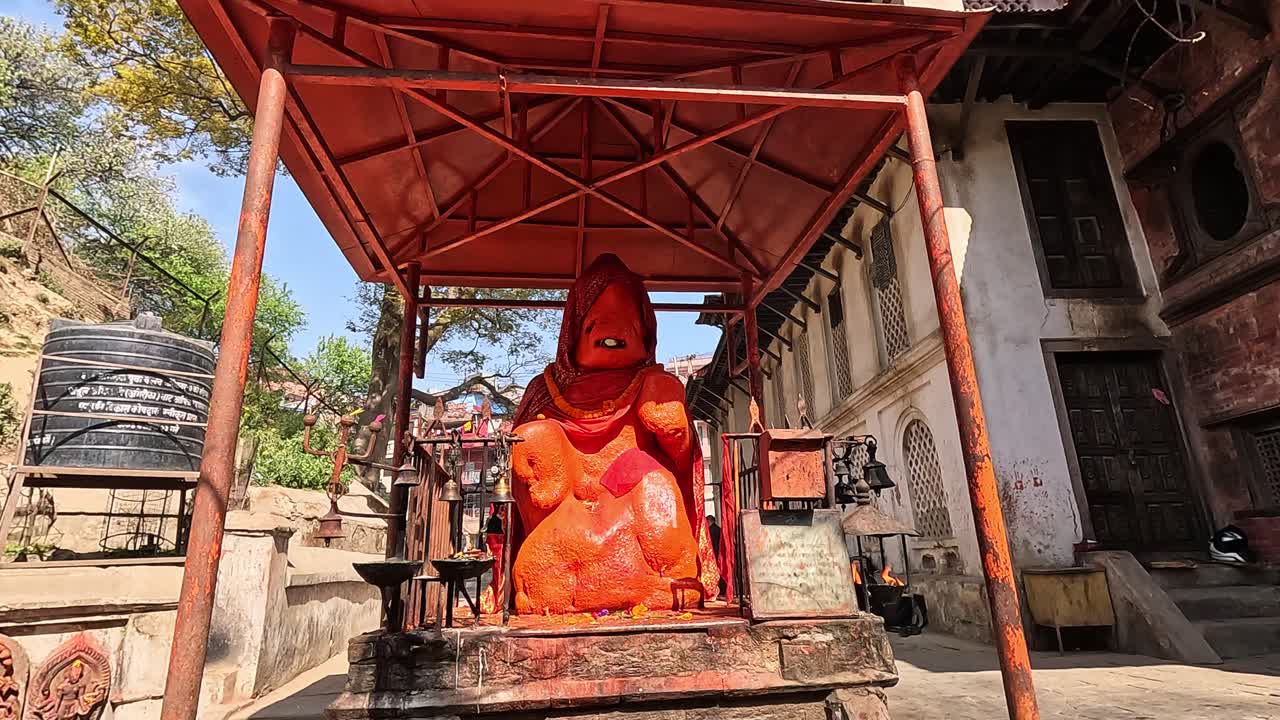 Faithful devotees gather to pray at the Gauri Temple pashupatinath, Kathmandu.  decorating the Hanuman statue covered in vibrant orange. A scene filled with spiritual devotion