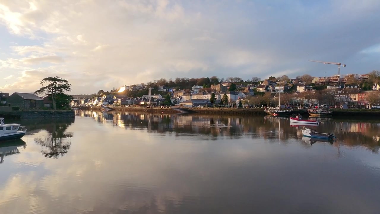 Muro a secco e riflesso sull'acqua in una mattina d'inverno a Kinsale, Irlanda, ripresa con drone in decollo