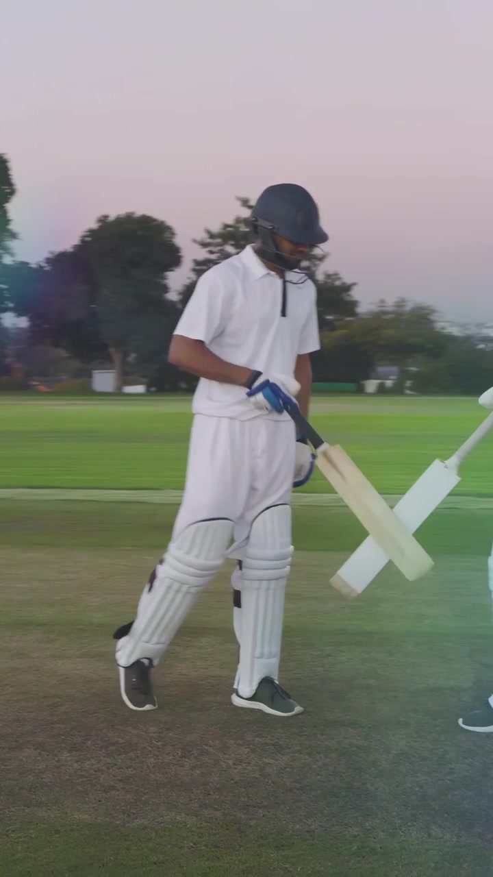 Vertikal video: Cricket-batsman tapper på hjelmen, går af banen efter at have battet, og partneren slutter sig til ham under lysene.