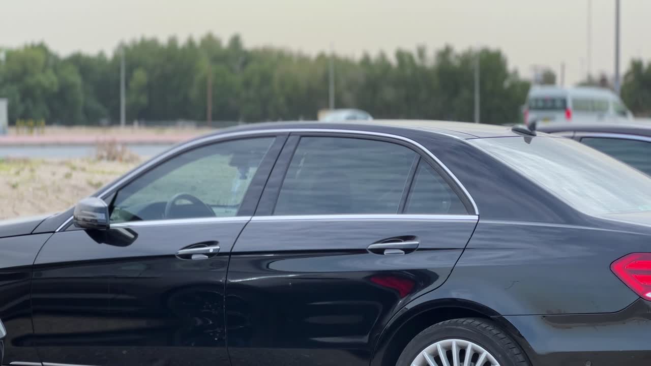 4K side view of a luxury black sedan parked in daylight. Ideal for automotive ads, driving scenes, transportation themes, or cinematic B-roll footage with urban sophistication.