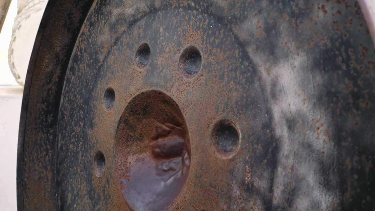 маленькая девочка потирает круглый металлический гонг, чтобы издать звук.