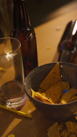 vertical video of messy table covered with empty wine glasses with beer bottles and snacks after house party 3