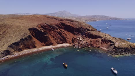 Aerial view of Red Beach in Santorini, Greece, with boats and swimmers