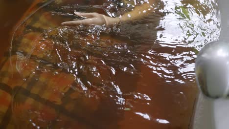 Mujer-Mano-Achicando-Hierba-El-Agua-Lentamente,-En-Jacuzzi