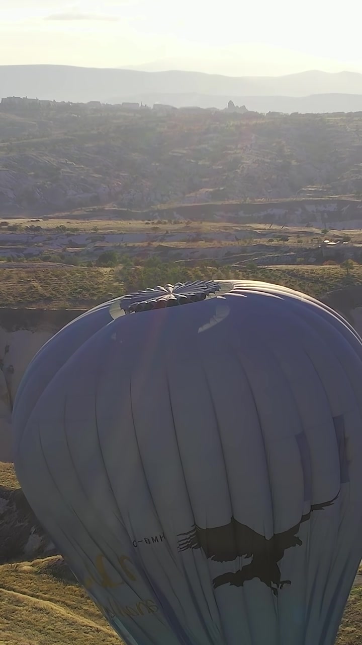 Mongolfiera sorvola il paesaggio della Cappadocia al tramonto.