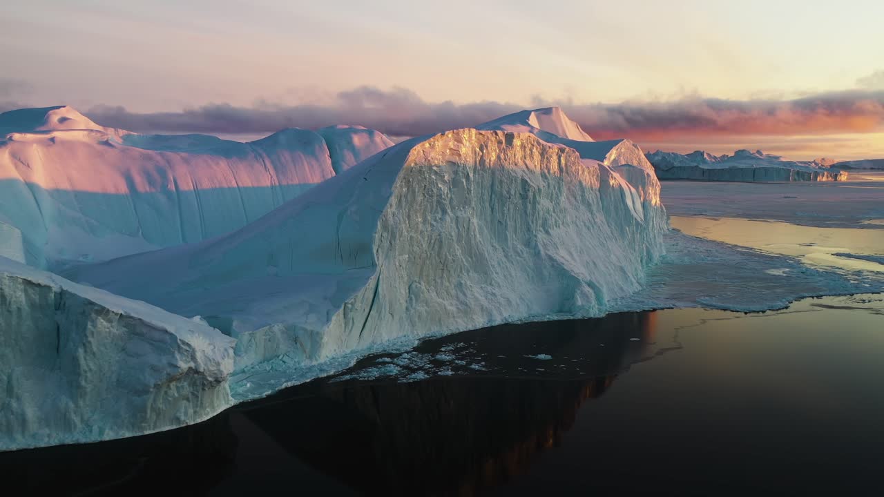vista aérea de los icebergs iluminados por el sol y el reflejo del mar tranquilo, dramática puesta de sol en groenlandia