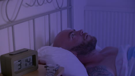 un hombre está acostado en la cama sin poder dormir