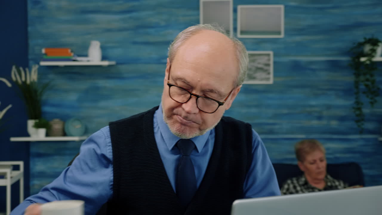 Close up of senior man writing at laptop working from home