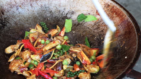 Cooking-stir-fried-sea-snail-dish-in-wok-with-spatula,-close-up