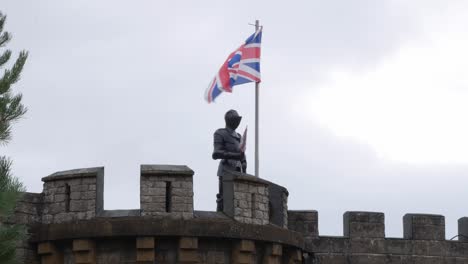 a british knight protecting a castle with the union jack flag fling on a pole.