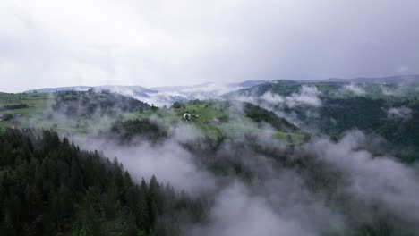 Luftaufnahme-Des-Dorfes-Auf-Einem-Grünen-Waldhügel-An-Einem-Nebligen-Morgen,-Siebenbürgen,-Rumänien