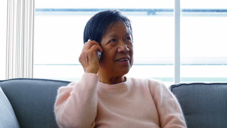 Senior-woman-talking-on-mobile-phone-in-living-room