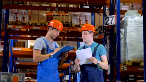 warehouse workers in hard hat working in a warehouse between storage racks. 4k.