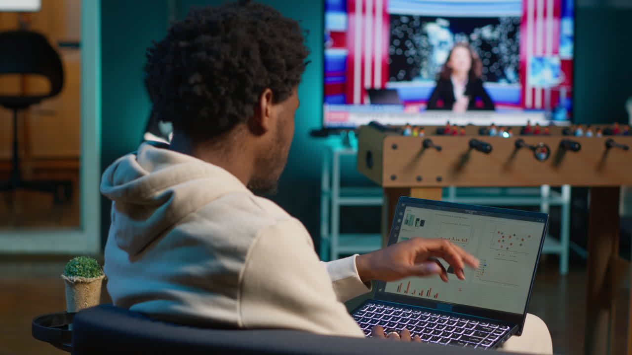 African american person working from home and checking statistical data on laptop screen, analyzing financial graphs. Teleworker in the living room comparing business revenue numbers. Camera A.