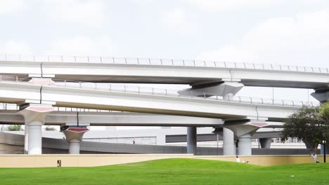 Lofty-Archways-Of-Dubai-Metro-Train-From-Al-Rashidiya-Park-With-People-Strolling-At-Daytime-In-Dubai