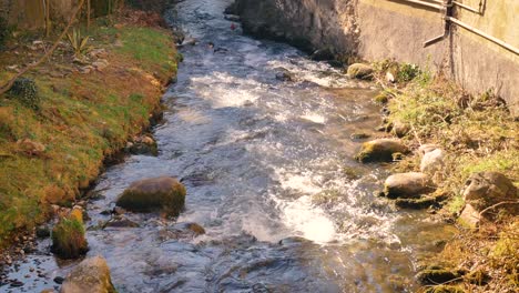 Una-Pequeña-Corriente-De-Agua-En-Un-Pueblo-Italiano-Pasa-A-Través-De-Los-Patios-Traseros-De-Las-Casas