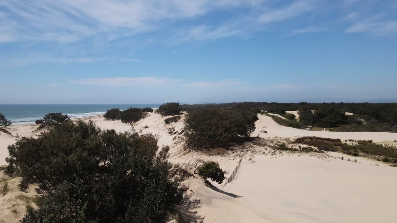 vista de drones en movimiento de un paisaje de dunas de arena nativo australiano que revela un horizonte de ciudad distante