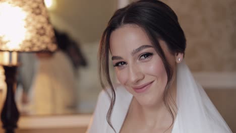 beautiful bride in white boudoir dress looking at camera and smiling, wedding morning preparations