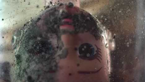 centered doll face sits in water as tiny micro bubbles dance and drift upward in a creepy dramatic fashion