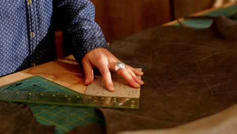 mid-section of craftswoman measuring leather with scale