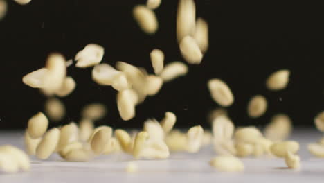 close up shot of peanuts dropping onto marble surface against black studio background shot in slow motion