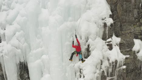 single climber on frozen ice cascade preparing safety line 4k