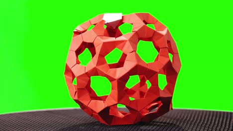 red modular origami ball on green screen.