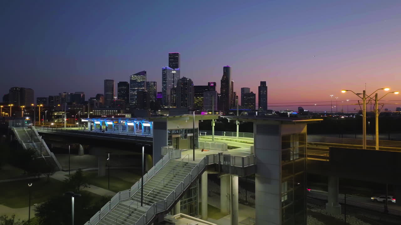 Aerial view of a Metro arriving at a station, Houston skyline backdrop, twilight
