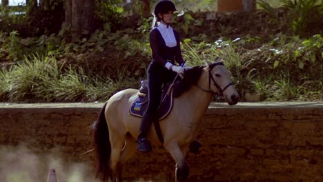 A-beautiful-woman-sits-atop-a-light-brown-horse-in-slow-motion