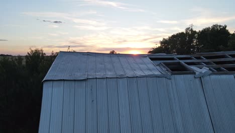 Aerial-flyover-shot-of-two-abandoned-barns-reveals-epic-countryside-sunset-in-the-prairies