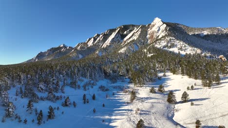 amanecer aéreo drone amanecer sobre las montañas flatiron y el parque histórico de chautauqua en boulder, colorado en una mañana de invierno cubierta de nieve