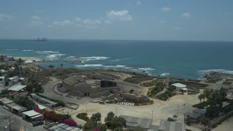 Aerial-view-of-The-Roman-Amphitheater-of-Caesarea-and-the-ancient-remains-of-the-coastal-city-of-Caesarea,-built-under-Herod-the-Great-during-22–10-BC