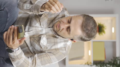 Vertical-video-of-Man-listening-to-music-with-headphones-is-unhappy-and-sad.