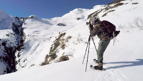 un fotógrafo de naturaleza y vida silvestre se prepara para una sesión de fotos de invierno en las montañas cubiertas de nieve de la isla de kodiak, alaska
