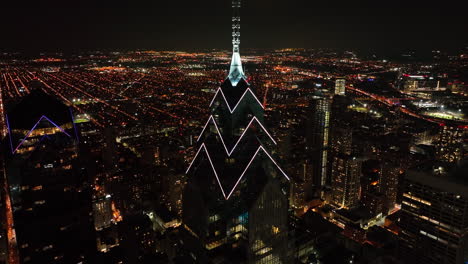 Rising-aerial-at-night-reveals-dramatic-skyscraper-tower-in-darkness