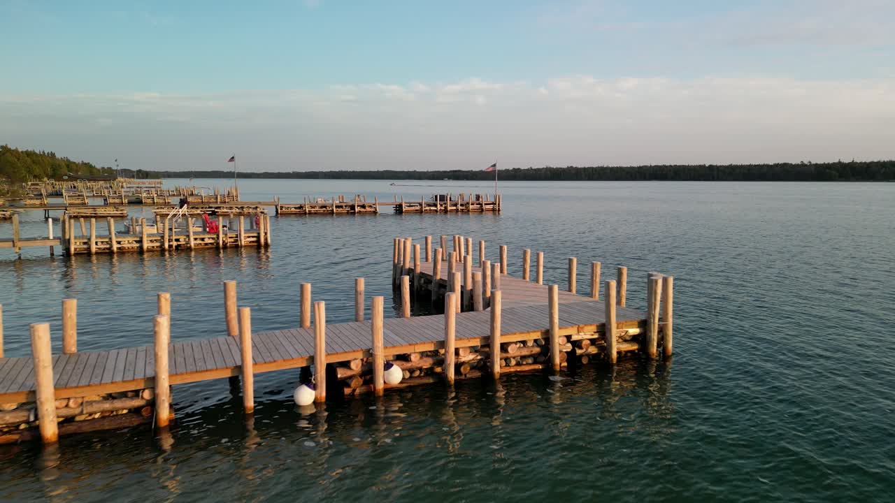 Sorvolo aereo di pontili illuminati dall'ora d'oro in riva al lago