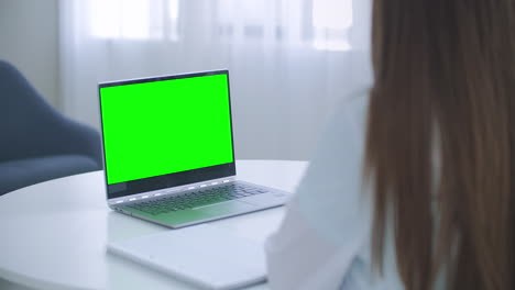 la mujer está consultando en línea portátil con pantalla verde en la mesa concepto de llave croma