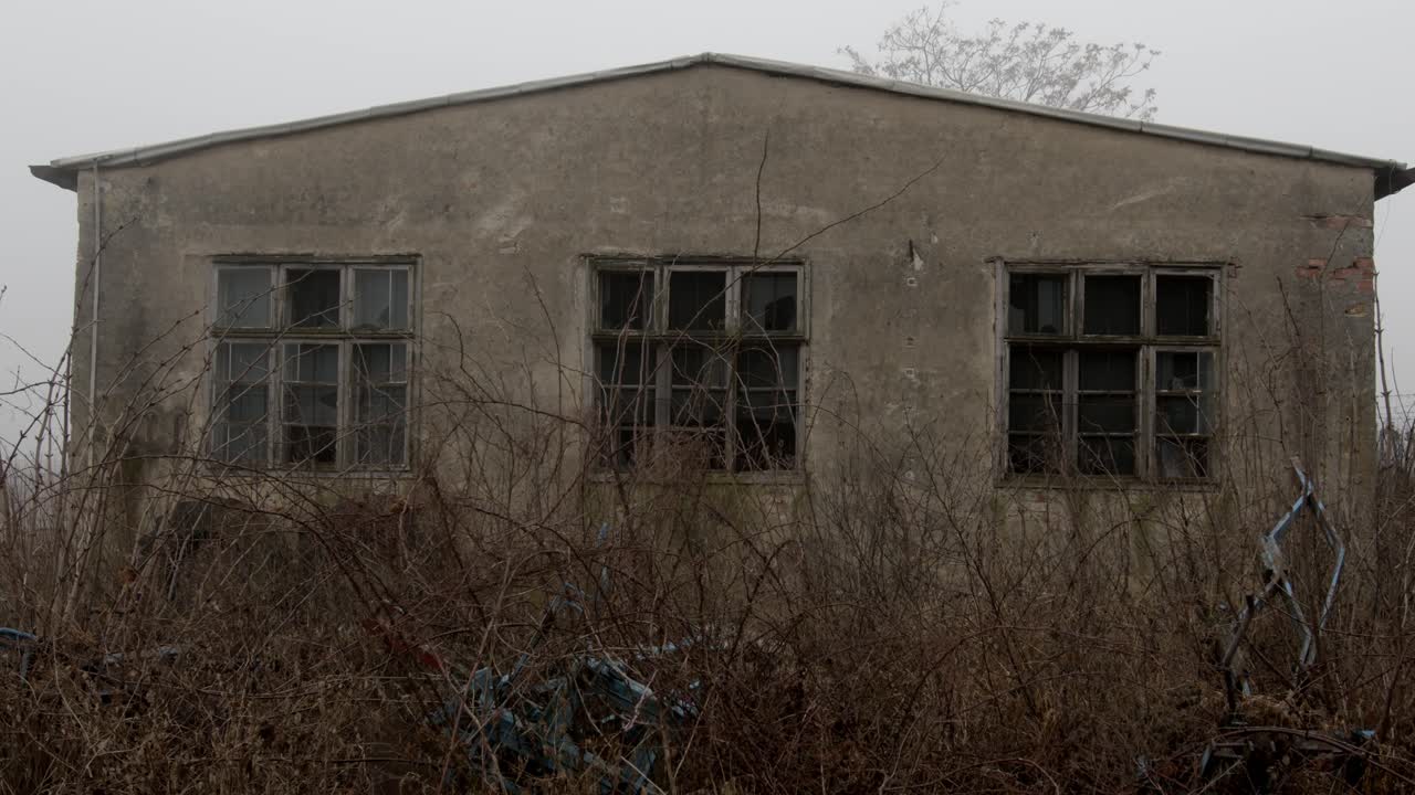 Slow, suspense dolly shot, of an abandoned building with broken windows.