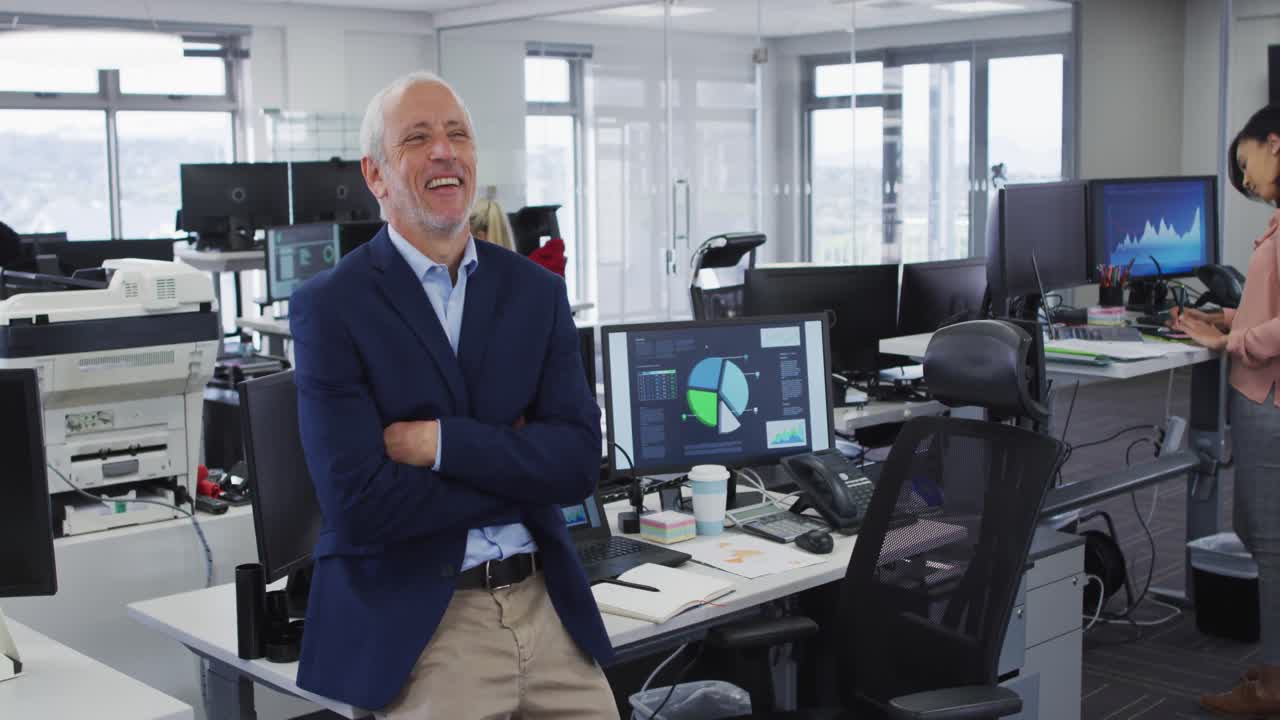 hombre cruzando los brazos y sonriendo mientras está de pie en la oficina