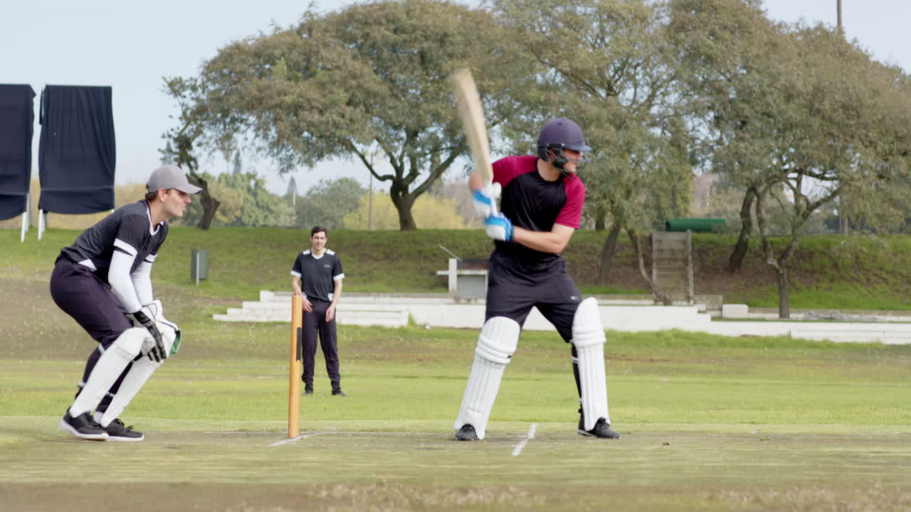 Two teams of male cricket players playing cricket on pitch