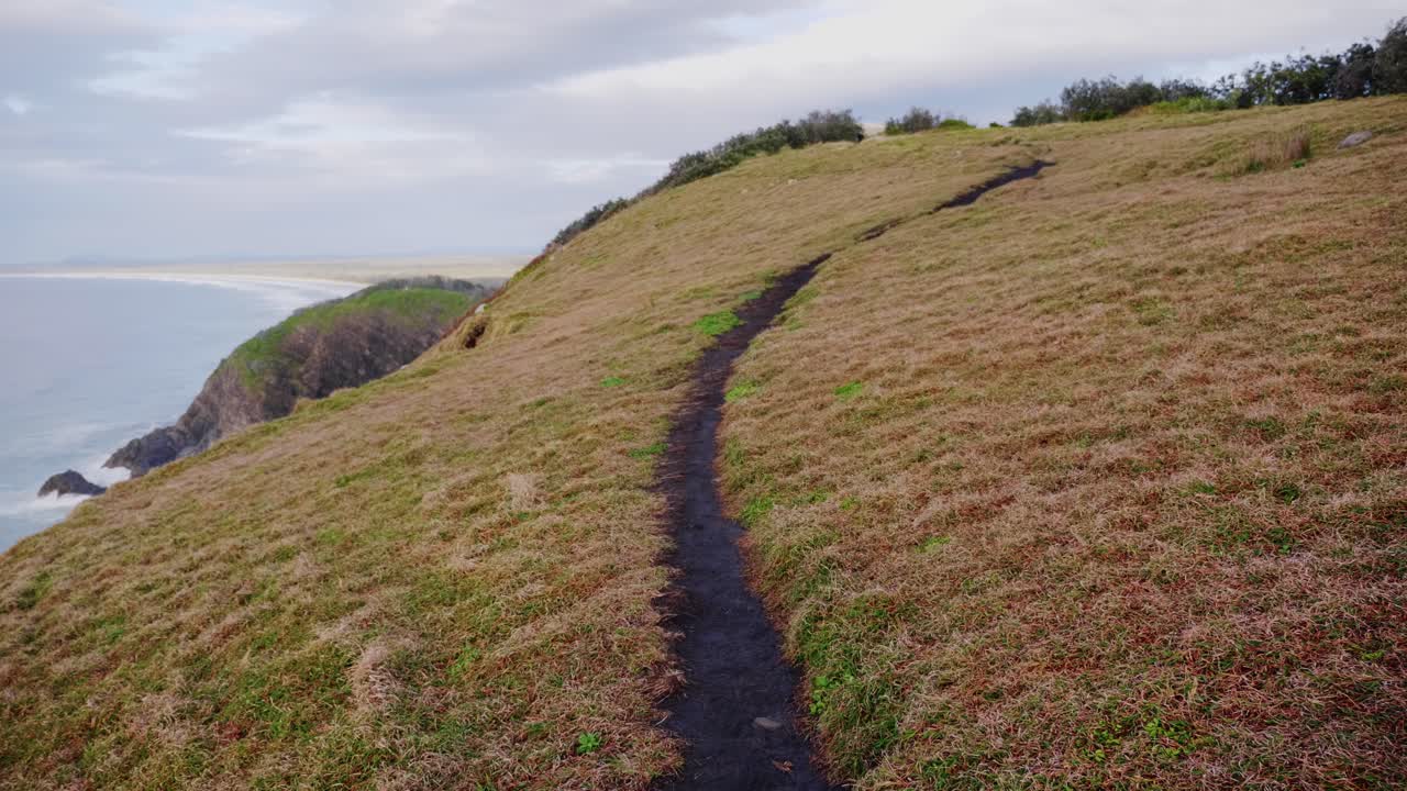 vista de ángulo bajo del camino estrecho en la montaña cubierta de hierba - cabeza de media luna, nsw, australia - tiro estático