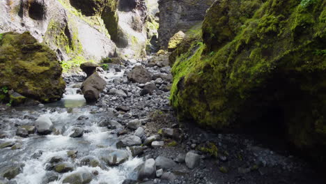 A-dynamic-flight-near-cliffs-above-a-river-flowing-on-big-rocks-on-the-bottom-of-a-ravine