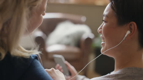 friends at home hanging out on the sofa sharing earphones listening to music