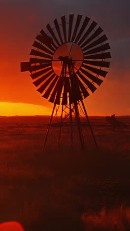 a windmill is in the middle of a field with a beautiful sunset in the background. the scene is peaceful and serene, with the windmill standing tall and proud in the midst of the vast, open landscape