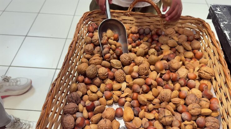 Close-up view of the hands of a young black mother and her son playing with assorted nuts in a basket. slomotion shot