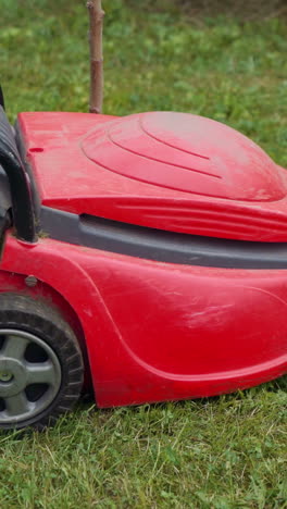 cutting fresh green grass with lawn mower. barefoot young girl mowing grass with a lawn mower in garden. vertical video