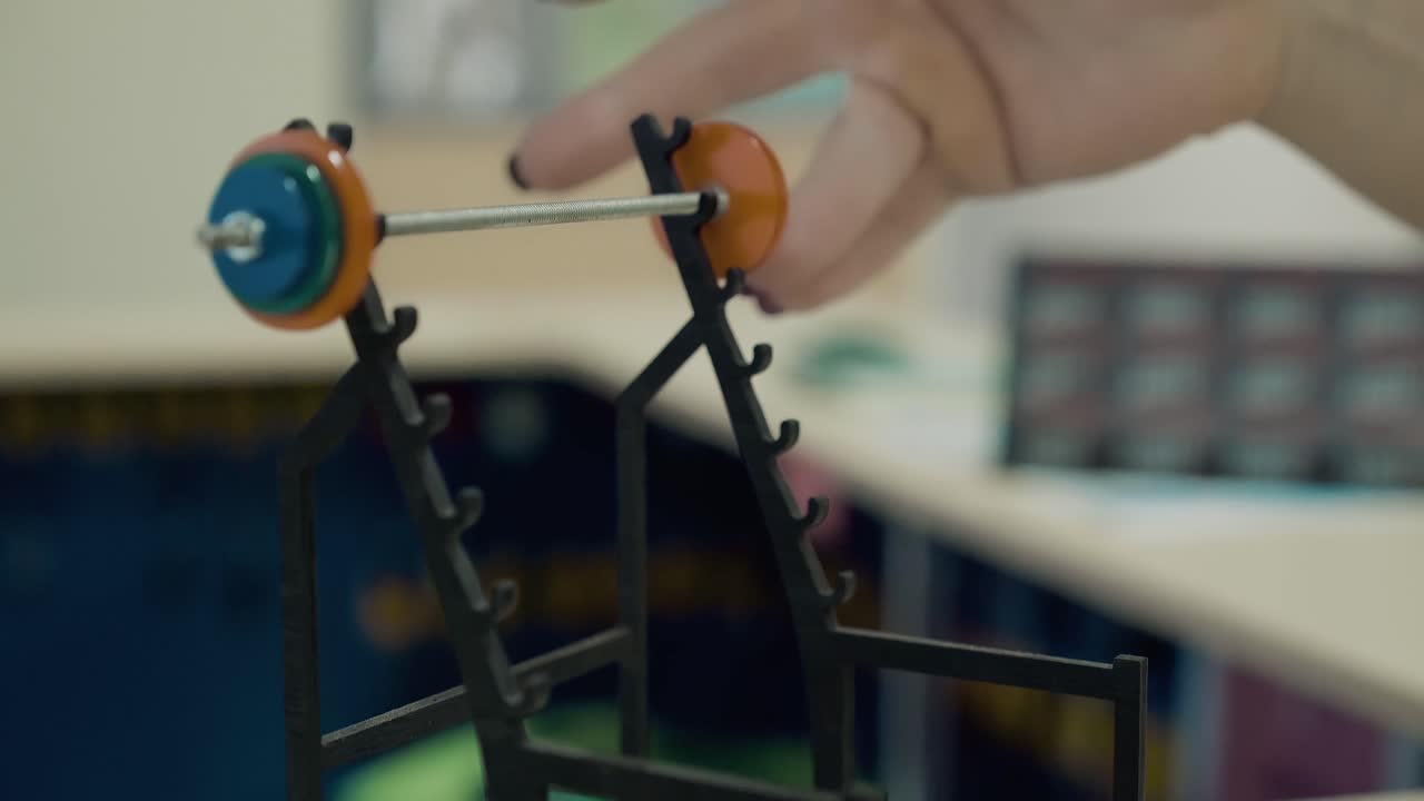 Young girl athletic in the gym She lifts a small barbell model with two fingers Close-up